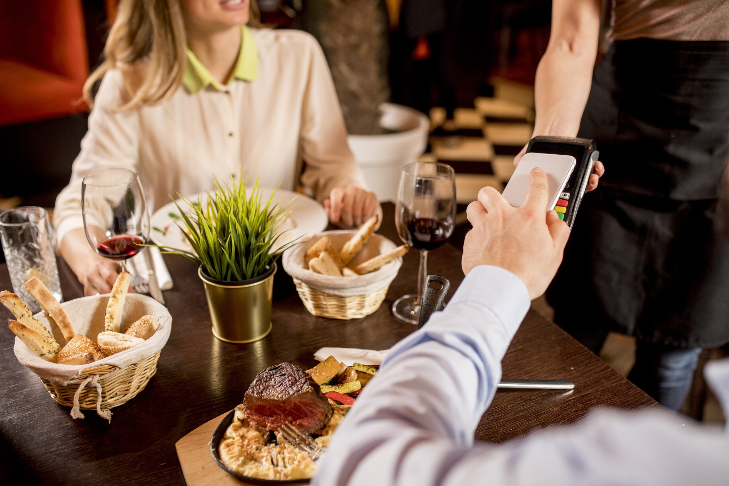 Man paying with NFC technology on mobile phone at the restaurant